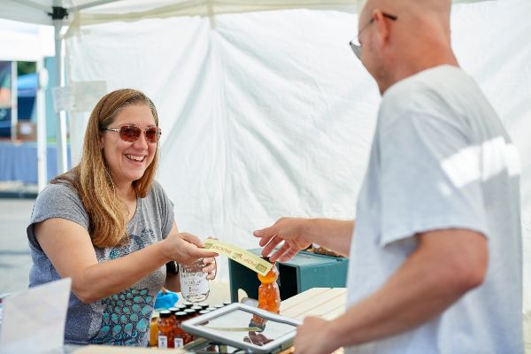 Woman paying for a drink at a concession stand at an outdoor benefit